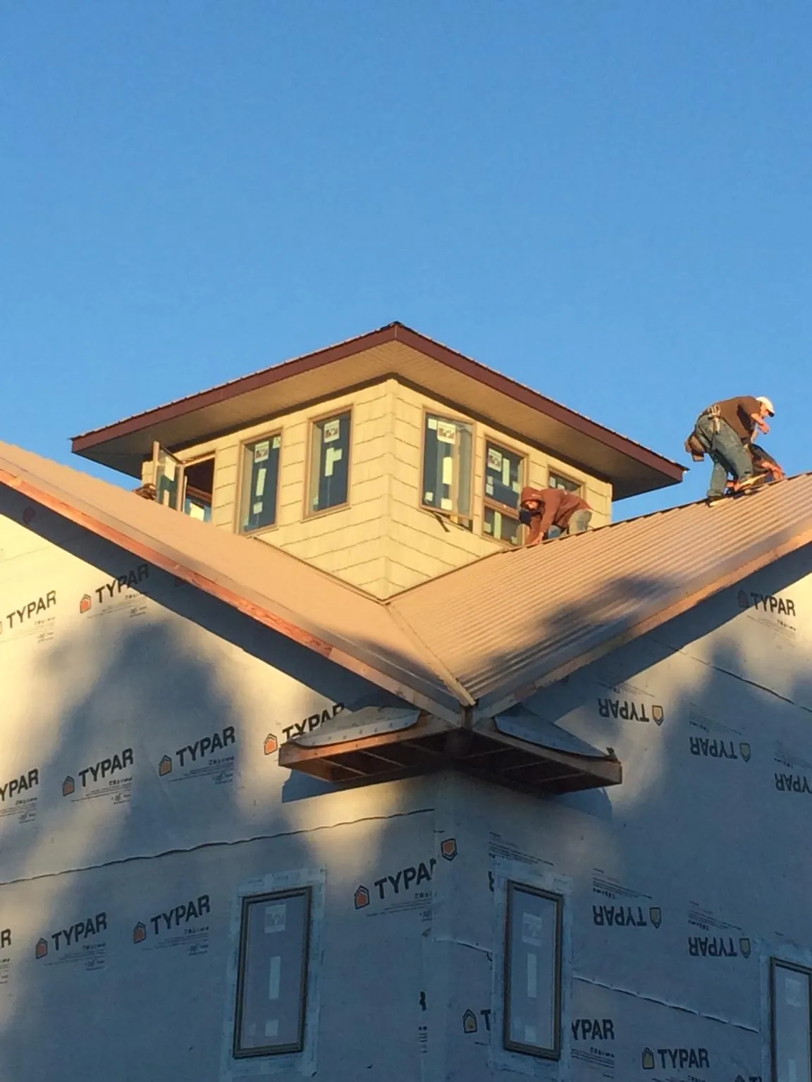 Roofers working around a rooftop cupola on a new metal roof at sunset — Roof Waterproofing in Little Switzerland by Roofing Brothers